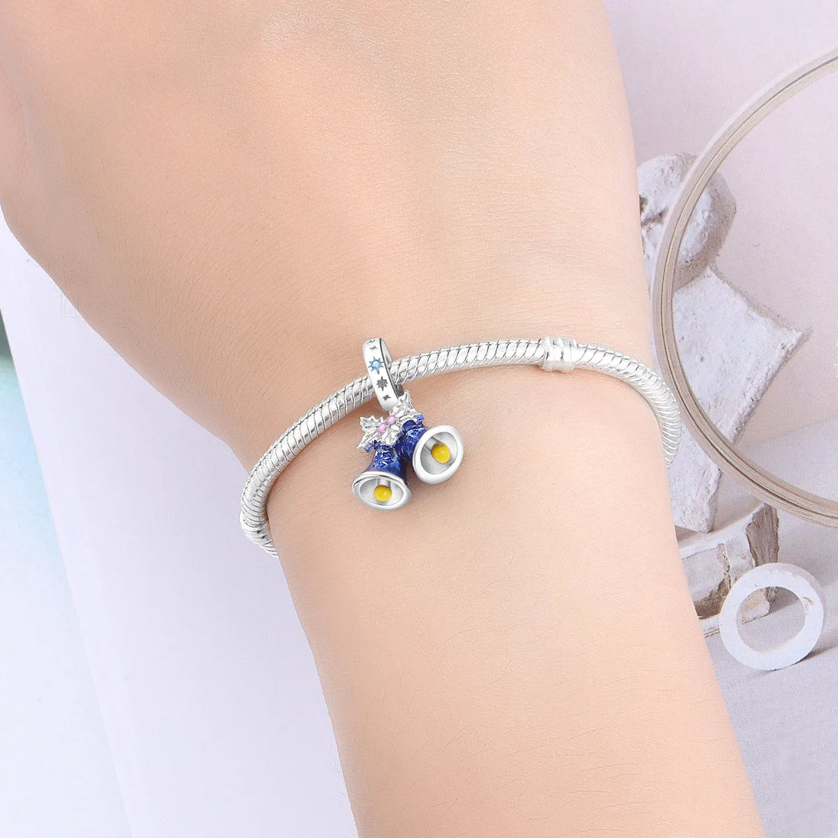 Silver bracelet with a decorative charm on a person's wrist against a light background