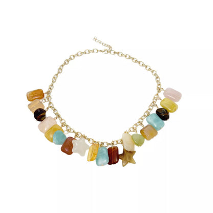 A gold-tone chain necklace featuring a row of colorful, irregularly shaped gemstone-like beads and charms in yellow, light blue, brown, pink, and white, displayed on a clean white background.