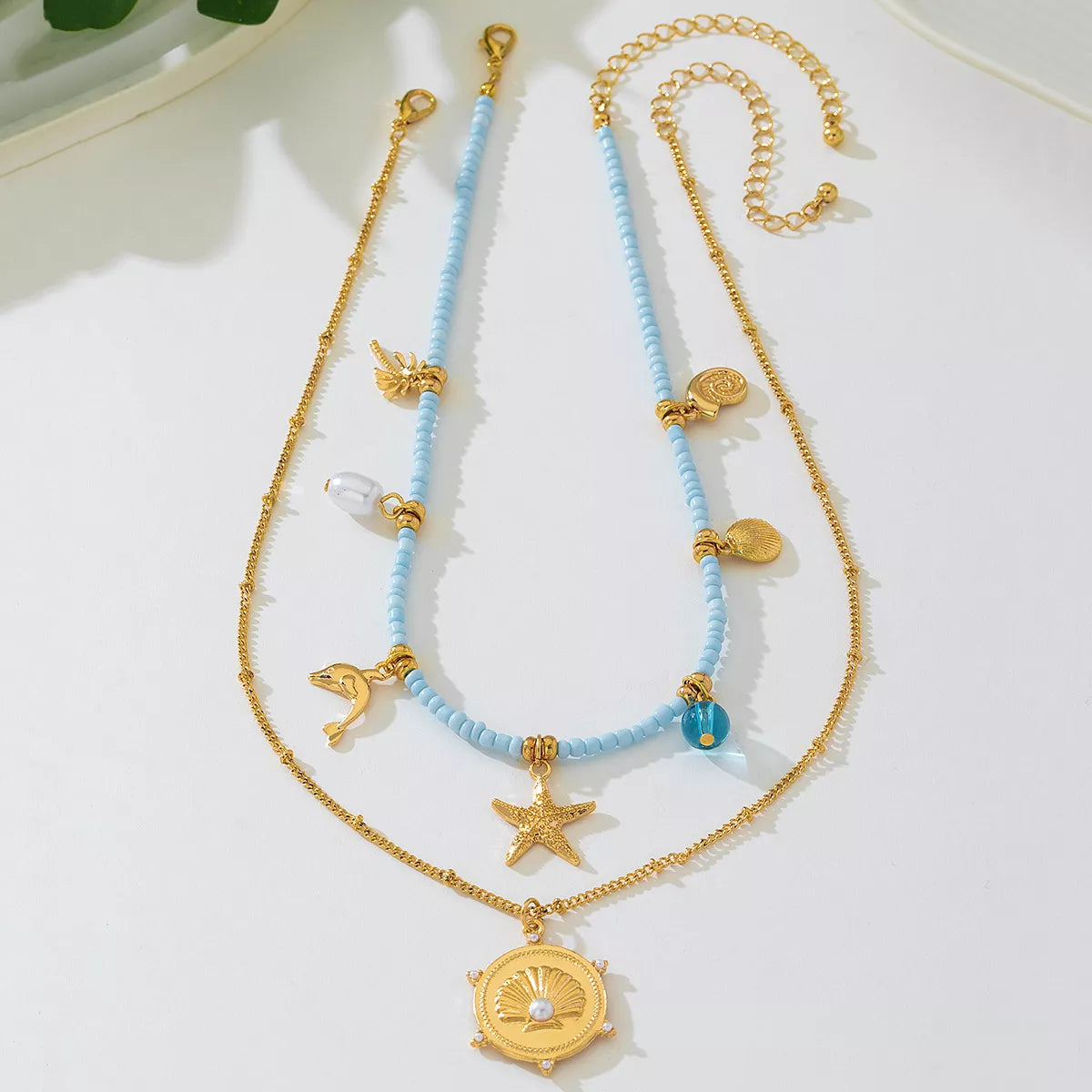 Two necklaces with blue beads and gold accents on a white surface