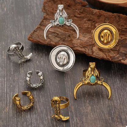 Collection of various western cowboy jewelry pieces including rings and pendants on a wooden surface.
