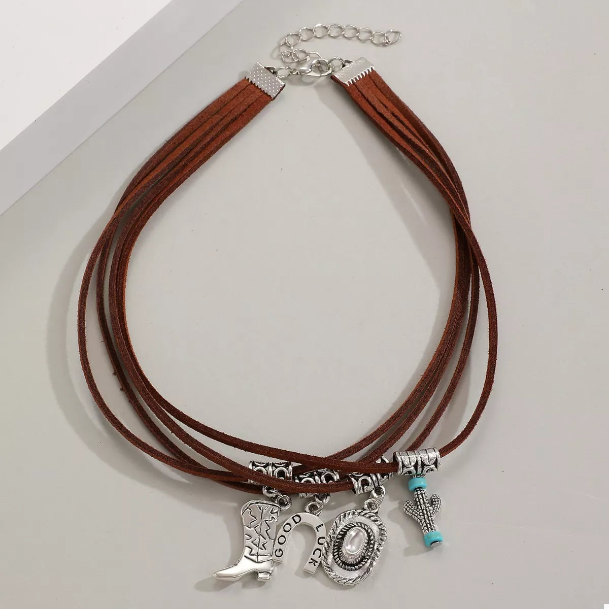 Brown leather necklace with silver western charms on a white background