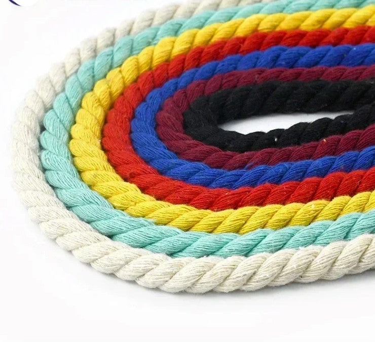 A coiled multi-colored macrame rope or cord with concentric bands of off-white, mint green, yellow, red, blue, and black on a plain white background.