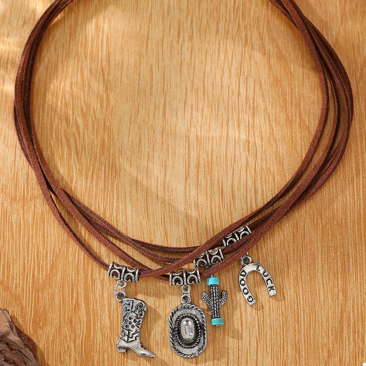 Brown leather cord necklace with silver western charms on a wooden surface