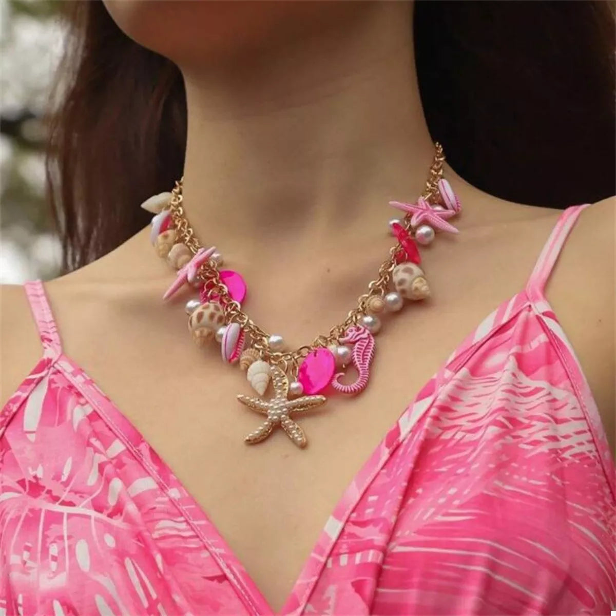 Necklace with pink and gold accents worn by a person in a pink top.