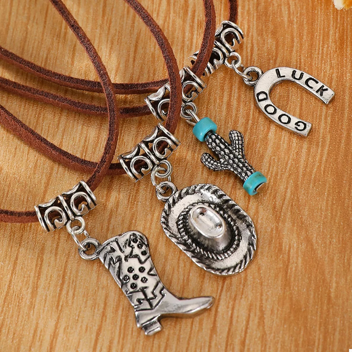 Necklace with cowboy boot, hat, and cactus charm on a wooden surface