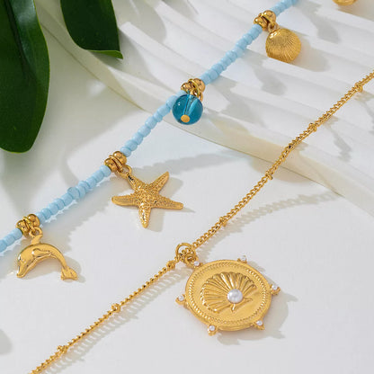 Gold necklaces with starfish, dolphin, and shell charms on a light blue beaded chain.