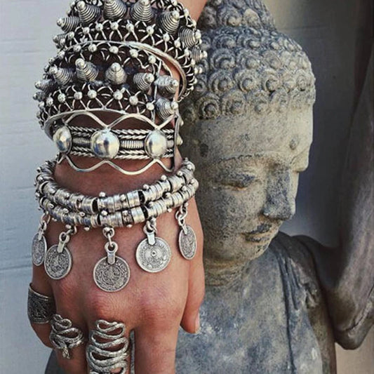 Silver jewelry set on a hand with a Buddha statue in the background