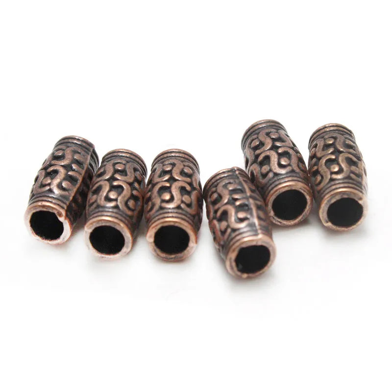 Five copper-colored metal spacer beads with embossed scrollwork patterns, arranged on a plain white background.