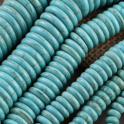 Close-up of multiple strands of turquoise-colored round beads with natural brown veining, arranged diagonally on a dark textured surface.