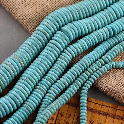 Turquoise round disc beads arranged in strands on a burlap and bamboo mat background.