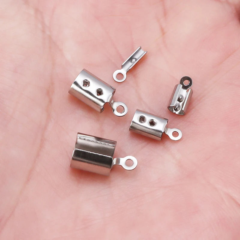 Five small silver bead cap tie connectors with loop ends, displayed on a pink skin surface.