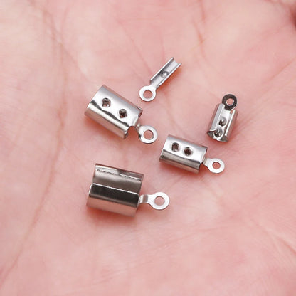Five small silver bead cap tie connectors with loop ends, displayed on a pink skin surface.