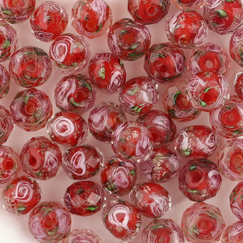Close-up of red and pink glass beads with floral patterns on a pink background