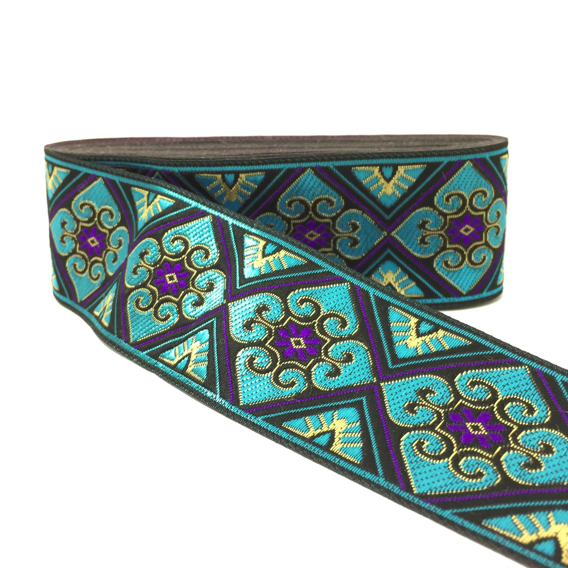A roll of decorative embroidered trim featuring a geometric pattern in turquoise, purple, black, and gold on a white background.