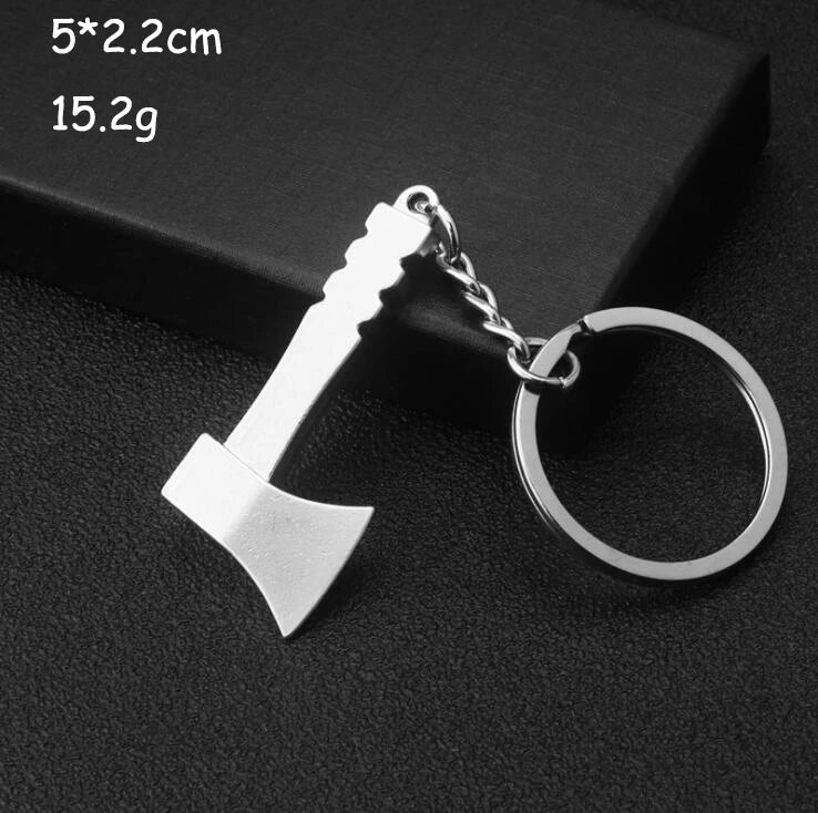Metal keychain shaped like a small axe on a dark background