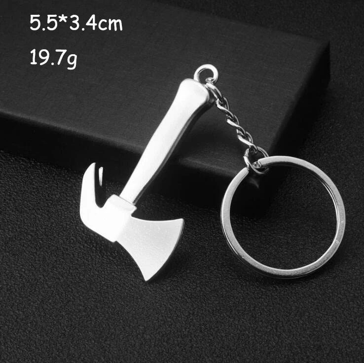 Silver axe-shaped keychain on a black background with measurements displayed.