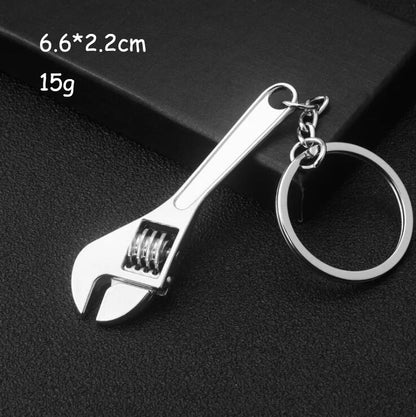 Wrench-shaped keychain on a black background with dimensions and weight displayed.