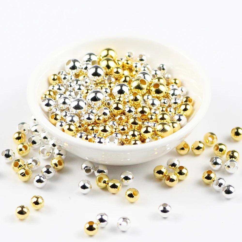 Gold and silver beads in a white bowl on a white background