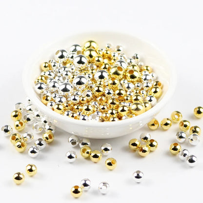 Gold and silver beads in a white bowl on a white background