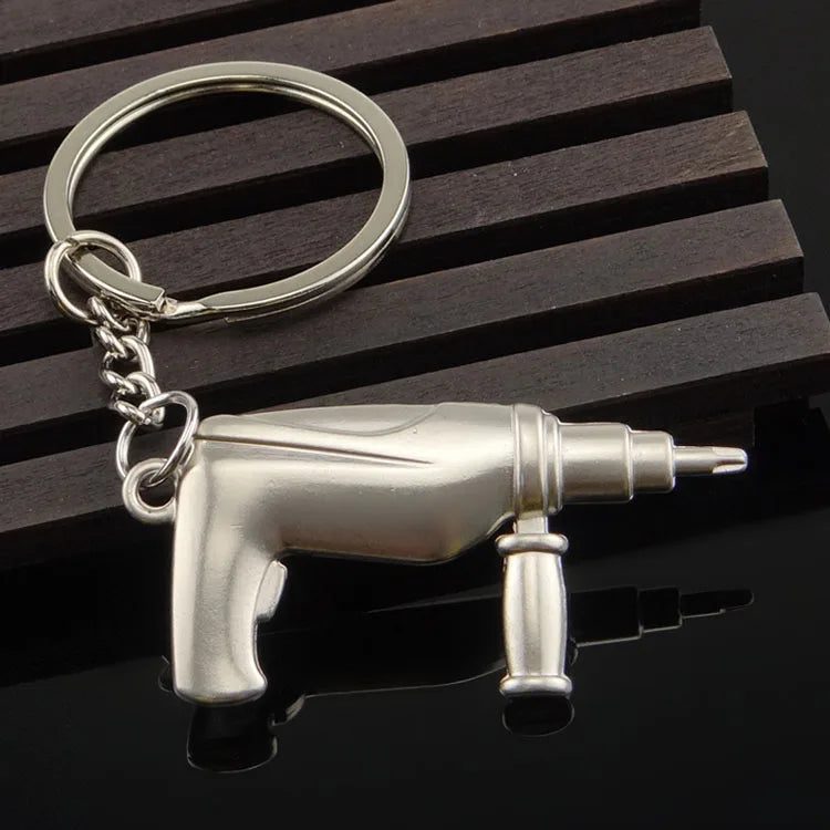 Metallic drill-shaped keychain on a dark wooden surface