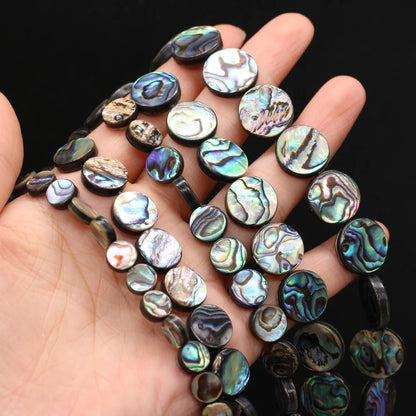 Abalone shell beads on a hand against a dark background