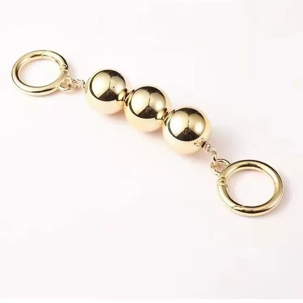 A gold-colored metal massage keychain featuring four polished oval beads connected by short chains to two circular key rings, shown on a plain white background.