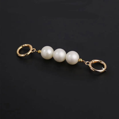 Pearl charm with gold loops on a black background