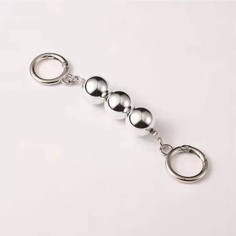 Silver keychain with spherical beads on a light pink background