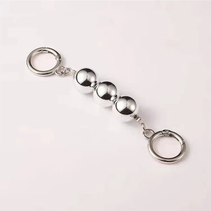 Silver keychain with spherical beads on a light pink background