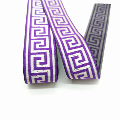 Purple and white patterned grosgrain ribbon with a vintage boho design, shown in two loops on a white background with a second roll visible behind.