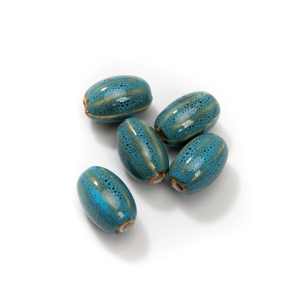 Five glossy turquoise-blue oval beads with tiny dark speckles and a subtle metallic gold edge, arranged on a clean white background.