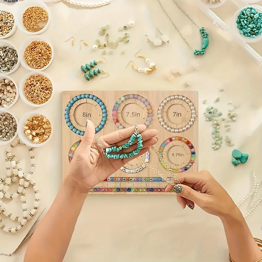 Jewelry-making setup with beads, tools, and a measuring beadboard on a light surface.