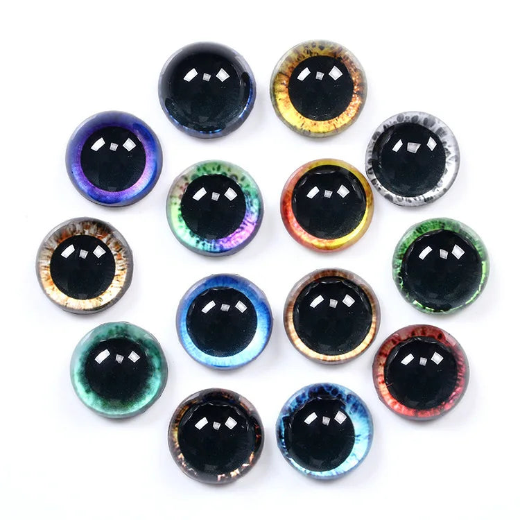 A set of 15 round, glossy faux-eye craft gems arranged in a circle on a white background. The gems feature realistic black pupils and various colorful iridescent and metallic iris patterns including blue, green, purple, gold, red, and brown.