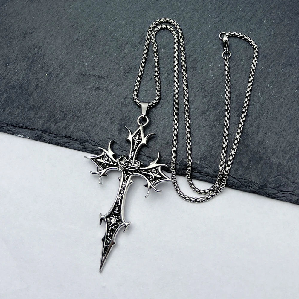 Silver cross necklace with detailed design on a dark stone surface