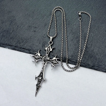 Silver cross necklace with detailed design on a dark stone surface