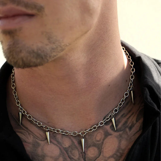 Man wearing a chain necklace with spike-like ends, close-up on neck and tattooed chest.