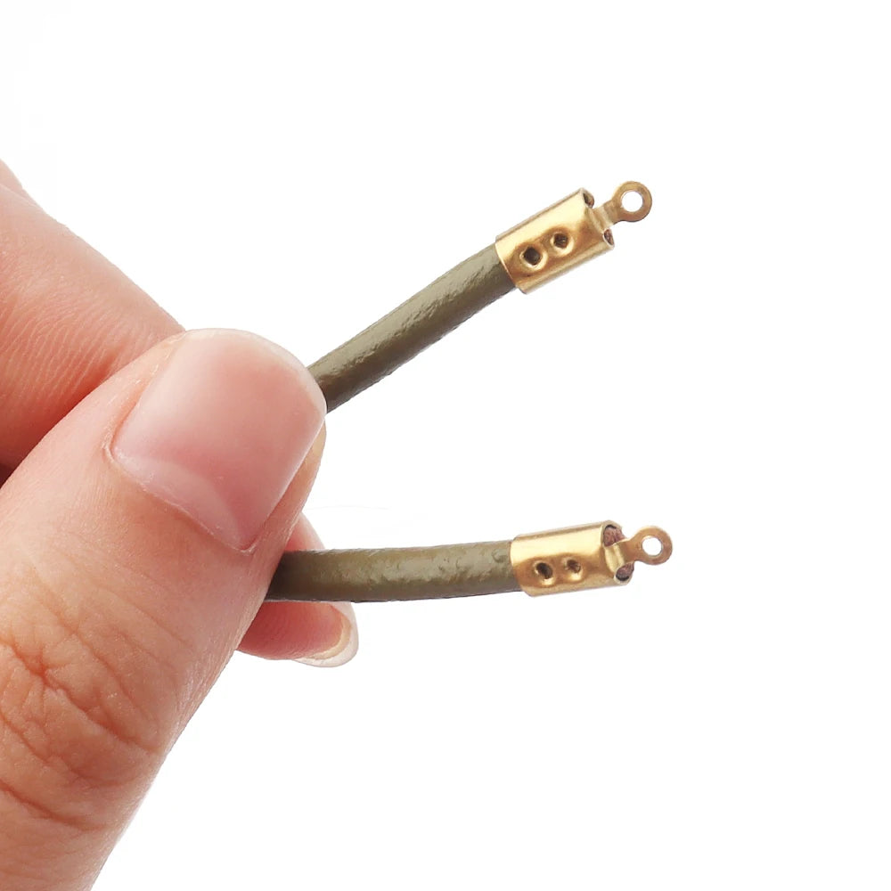 A close-up of a hand holding two olive green braided cords with gold-toned metal bead cap connectors against a plain white background.