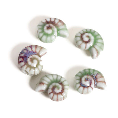 Five small spiral shell-shaped beads with a glossy finish, featuring a marbled pattern of green, white, purple, and reddish-brown, arranged in a circle on a white background.