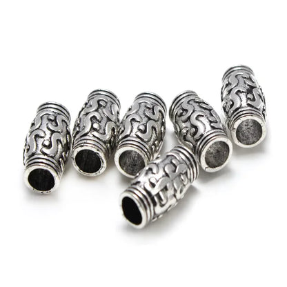 Five silver-toned cylindrical beads with intricate scrollwork and textured patterns, arranged on a plain white background.