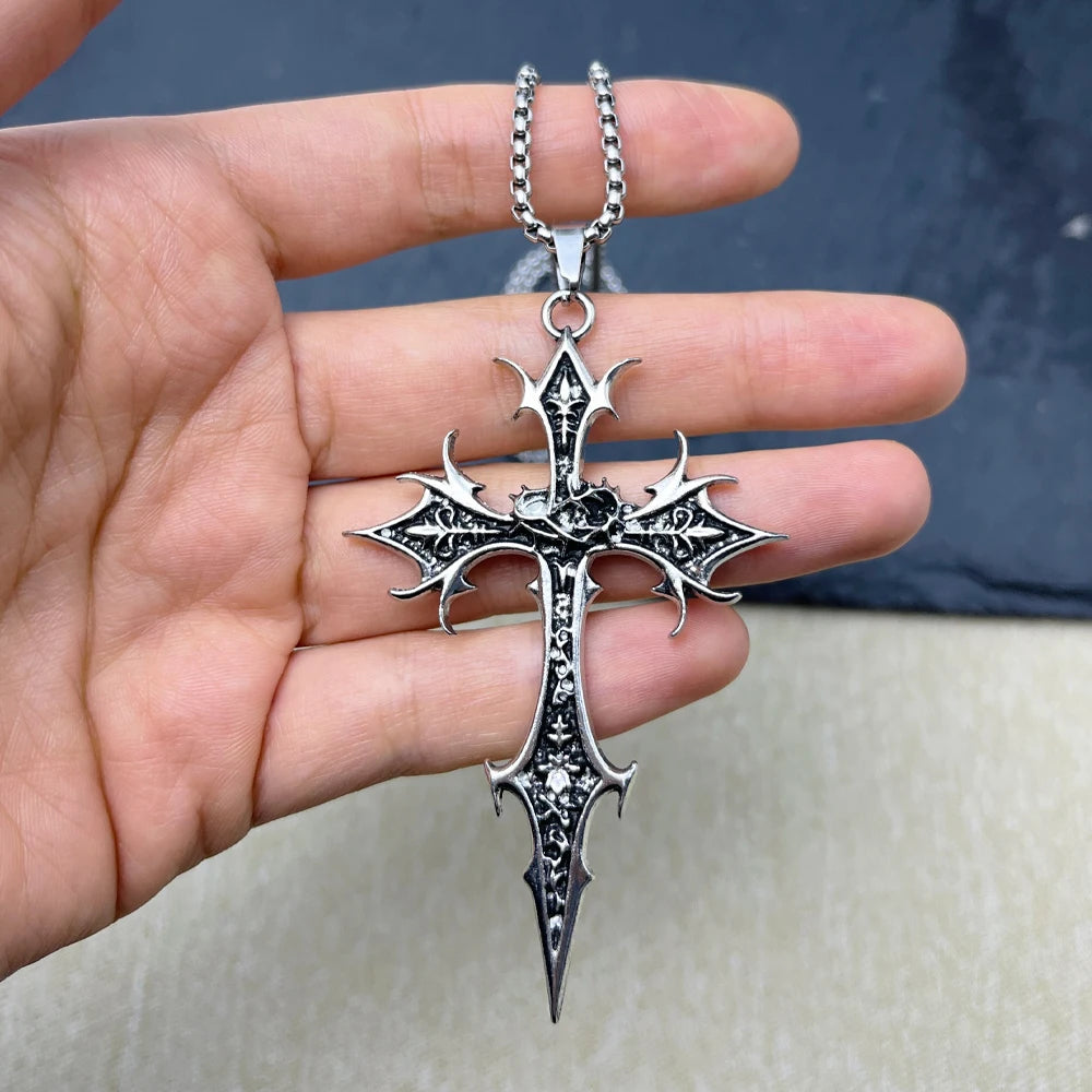 Silver cross pendant held in a hand with a blurred background