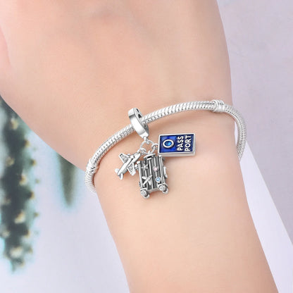 Silver bracelet with travel-themed charms on a wrist against a neutral background