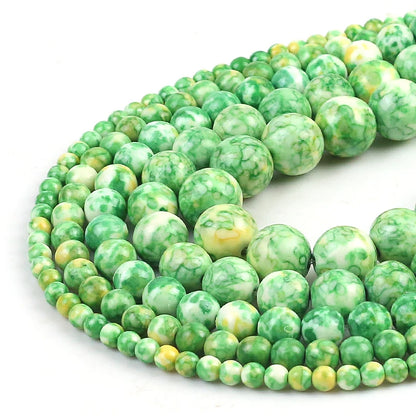 Green and white marbled round beads arranged in overlapping strands on a plain white background.