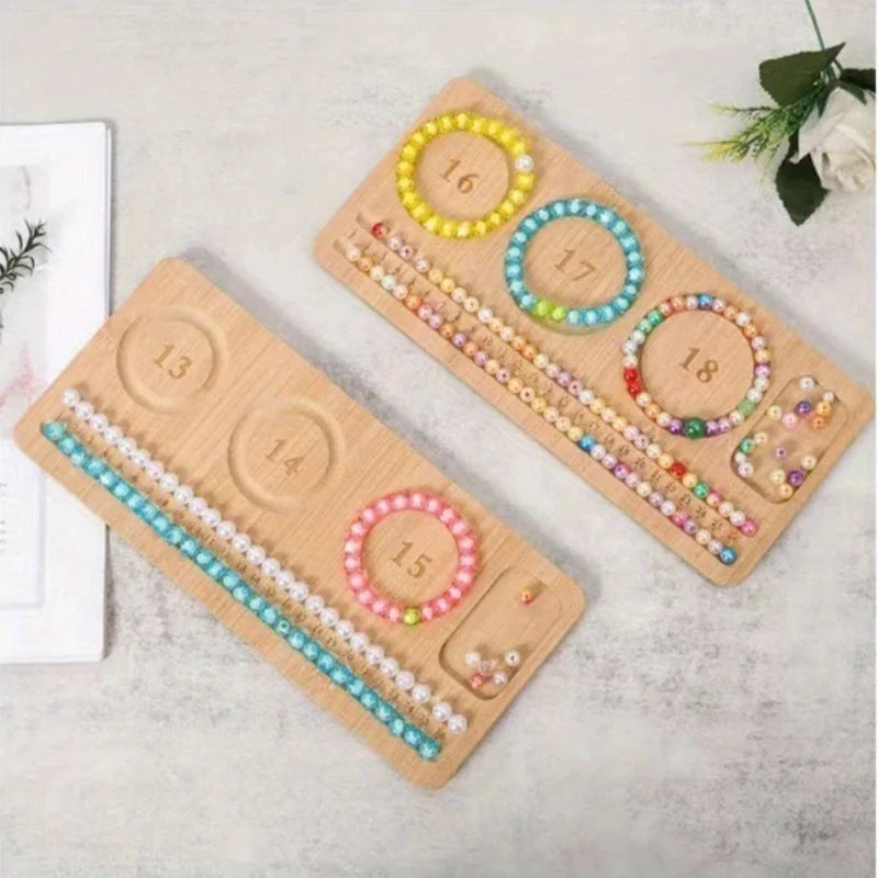 Two wooden jewelry-making trays with numbered compartments holding colorful beads and bracelet components, photographed on a light textured surface with small decorative props.