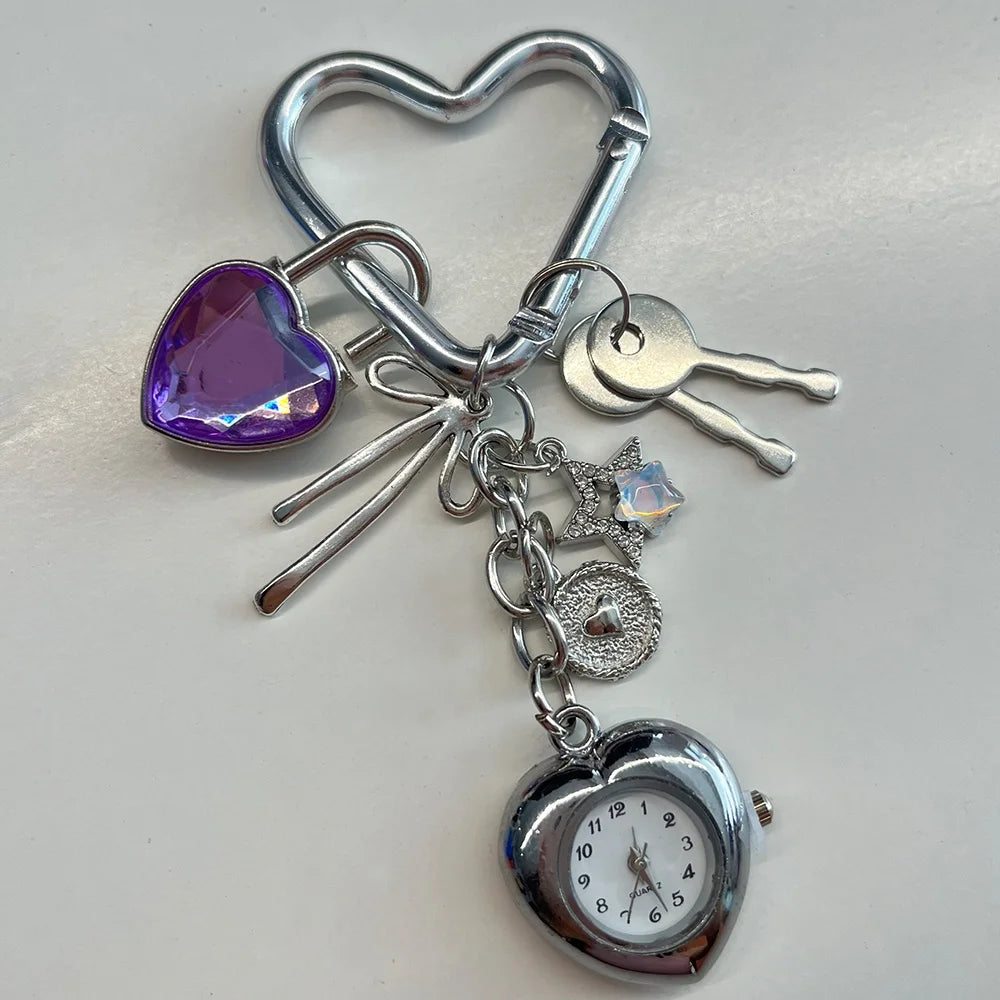 Heart-shaped keychain with charms including a clock, purple heart, and key on a light gray background