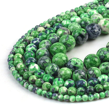 Multiple strands of round green marbled beads with dark blue and white speckles, arranged in a spiral on a plain white background.