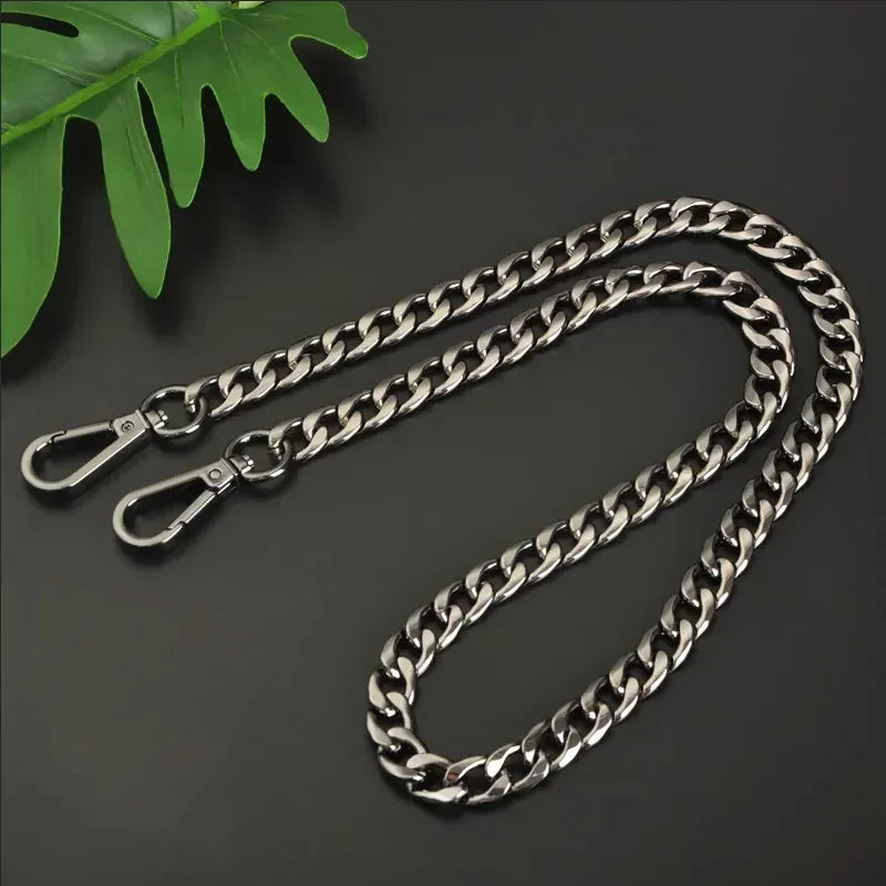 Silver chain with clasp on a dark surface with a green leaf