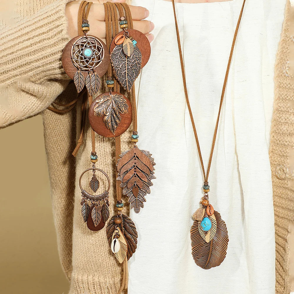 Decorative necklaces with feather and dreamcatcher designs on a neutral background