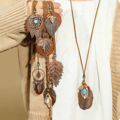 Decorative necklaces with feather and dreamcatcher designs on a neutral background