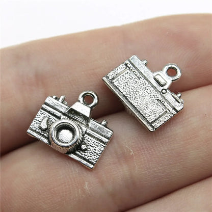 Two silver camera-shaped charms on a person's hand.