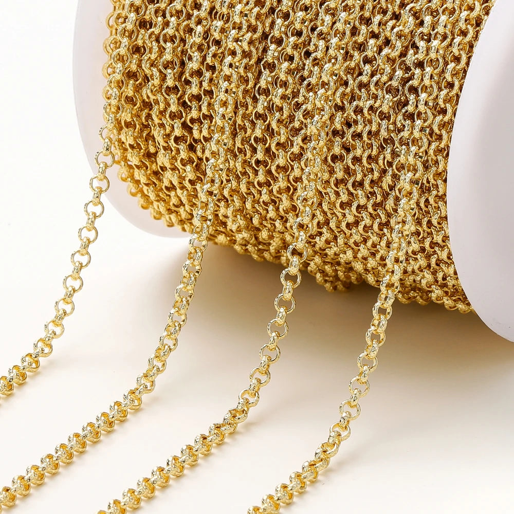 A close-up of a gold chain draped over a white spool, showing the fine interlocking links of the chain against a clean white background.